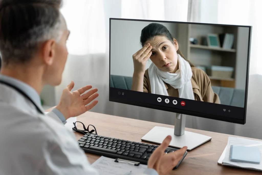 Psychiatrist speaking with a patient during an online video consultation, explaining symptoms and providing mental health support.