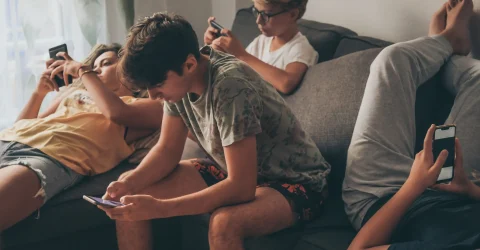 young-man-using-mobile-phone-home_11zon (1) teens using smartphones for gaming